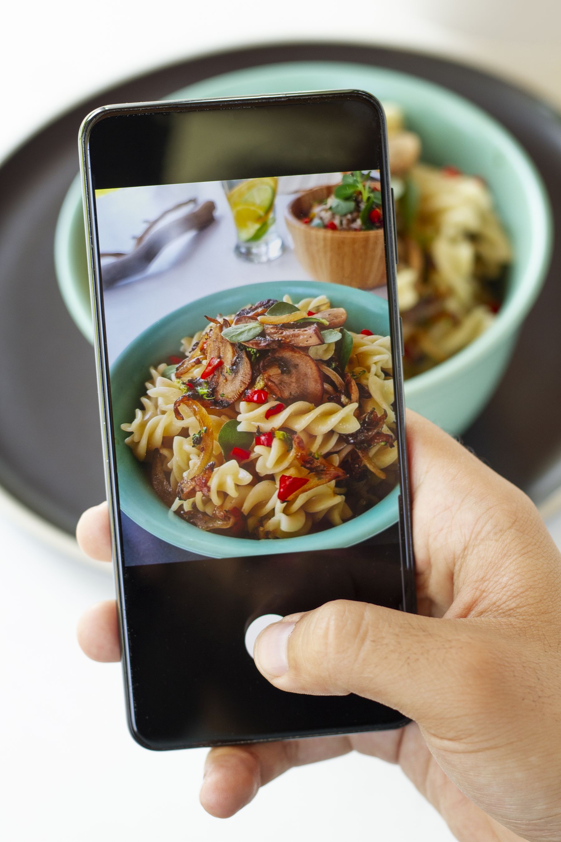Diner photographing a bowl of pasta with a smartphone